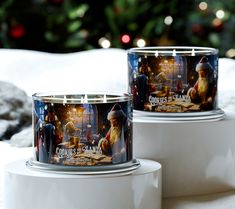 two christmas themed candles sitting on top of each other