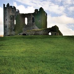 an old castle sitting on top of a lush green field