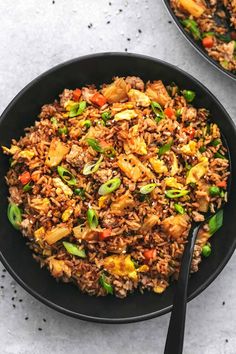 two black bowls filled with rice and vegetables