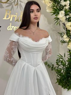 a woman in a white wedding dress standing next to a flower display with flowers behind her