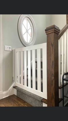 a white crib in a room with wood floors and a round window on the wall