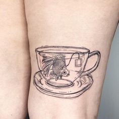 a fish in a coffee cup tattoo on the left side of the right leg,