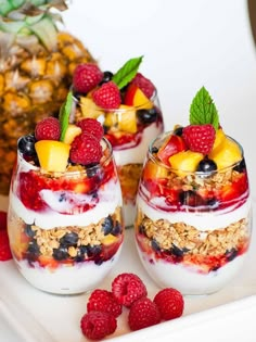 two glasses filled with fruit and yogurt on a plate