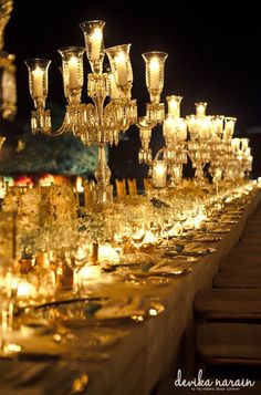 a long table is set with many candles and place settings for dinner guests to enjoy