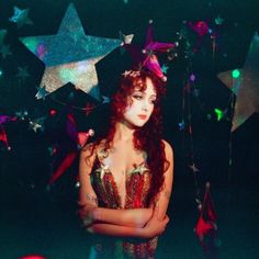 a woman with long red hair wearing a costume standing in front of stars