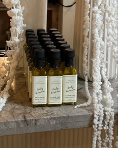 bottles of olive oil are lined up on a table in front of a white curtain