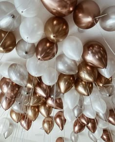 many white and gold balloons are hanging from the ceiling