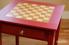 a small red table with a chess board on it's top and bottom drawer