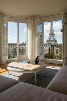 a living room with two couches and a coffee table in front of the eiffel tower