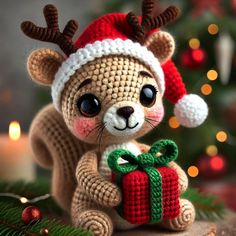 a crocheted teddy bear holding a christmas present