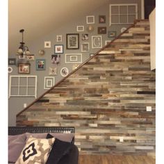 a living room filled with furniture next to a stair case covered in pictures and frames