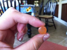 a person is holding an orange object in their left hand while sitting at a dining room table