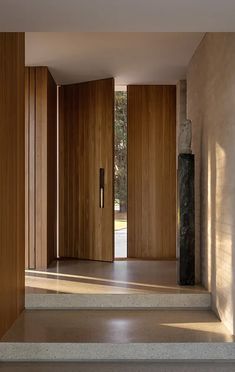 an open door leading into a room with wooden walls and steps that lead up to the second floor