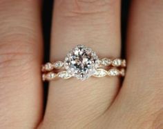 a woman's hand with a diamond ring on her left hand and the other hand holding an engagement ring