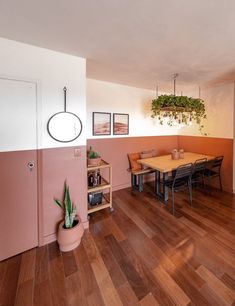 a dining room with wood flooring and pink walls, potted plants on the wall