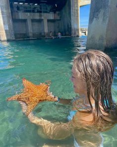 a woman holding a starfish in the water