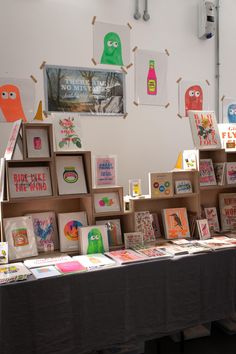 there are many greeting cards on display at the table in front of the wall with pictures