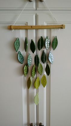 a wind chime with green leaves hanging from it's side on a door