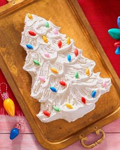 a cake with white frosting and multi colored sprinkles on it sitting on a wooden tray