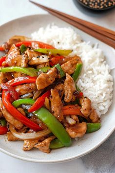 a white plate topped with chicken, peppers and rice