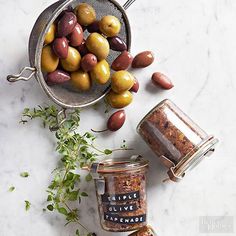 an assortment of olives and seasonings on a marble counter top