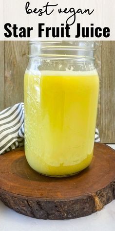 a mason jar filled with star fruit juice sitting on top of a wooden board next to a