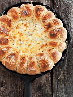 a skillet filled with bread on top of a wooden table