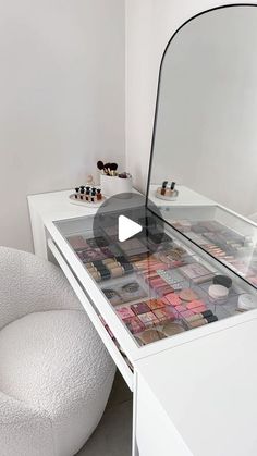 a white vanity with a mirror on top of it next to a chair and ottoman