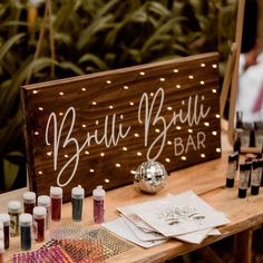 a wooden sign sitting on top of a table filled with bottles and paint tubes next to other items