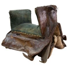 an old chair made out of pieces of wood and leather with a green cushion on it