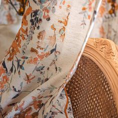 an orange and blue floral print fabric draped over a wooden chair with wicker seat