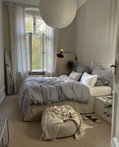 a bedroom with a large bed and two lamps hanging from it's ceiling above the bed