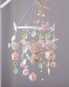 a stuffed animal is hanging from a mobile with flowers and butterflies on it's sides