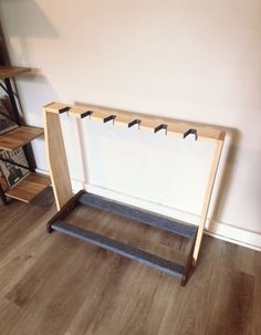 a wooden coat rack sitting on top of a hard wood floor next to a wall