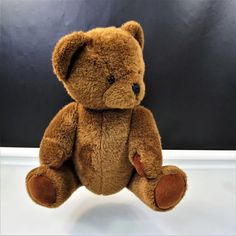 a brown teddy bear sitting on top of a white table