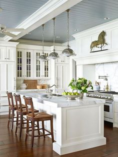 a large kitchen with white cabinets and wooden flooring, along with an island in the middle