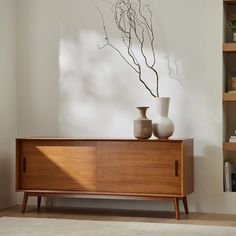 two vases sitting on top of a wooden cabinet