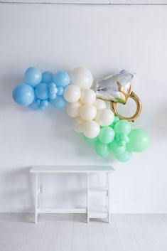 balloons are floating in the air next to a white bench and wall mounted coat rack