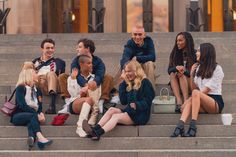 a group of people sitting on steps in front of a building with their hands up