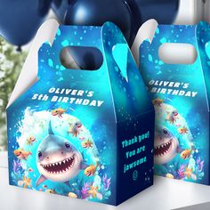 two shark themed birthday boxes with balloons in the background