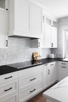 a kitchen with white cabinets and black counter tops is pictured in this image from the front view