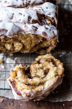 cinnamon roll with icing sitting on top of a cooling rack next to another pastry