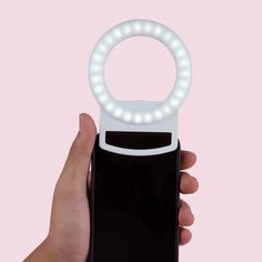 a hand holding a cell phone with a ring light on it's front cover