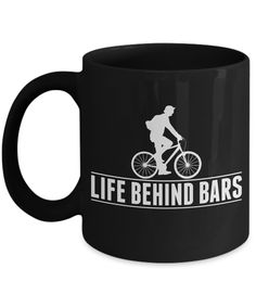 a black coffee mug with the words life behind bars on it and a man riding a bike