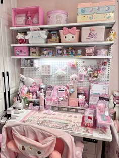 a room filled with lots of toys and accessories on shelves above a desk covered in pink sheets