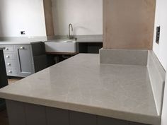 an empty kitchen with white counter tops and gray cabinets in the back drop off area