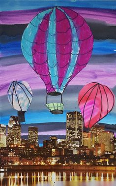 three hot air balloons flying over a city at night