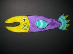 a purple and yellow fish shaped object on a black surface