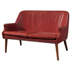 a red leather couch sitting on top of a wooden frame