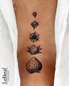 a woman's lower back tattoo with three flowers and rocks on her left side